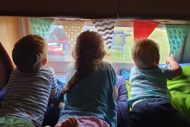 Die Kinder genießen morgens den Ausblick aus dem Wohnmobil