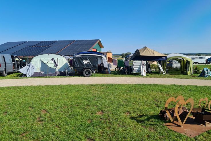 Ein Bild aus sonnigen Zeiten: unser Lager umfasst ein Zelt, ein Dachzelt auf dem Anhänger und zwei Pavillons.